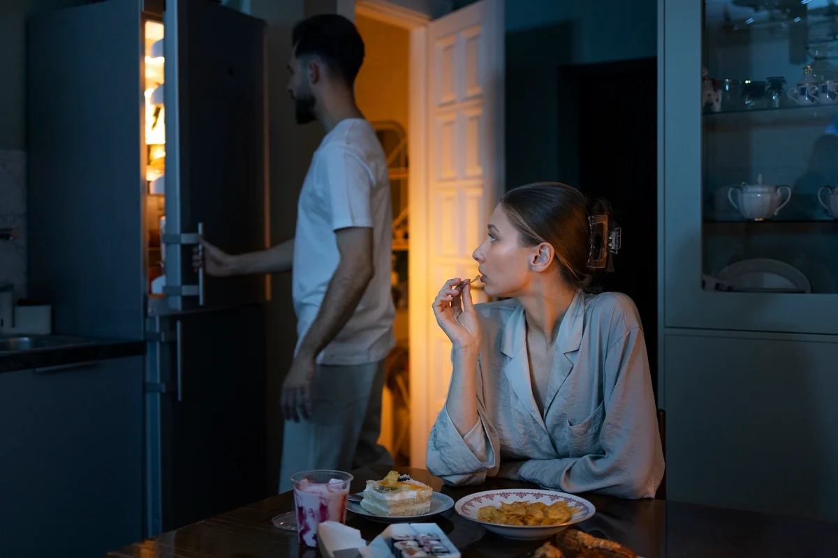 Imagem colorida de duas pessoas fazendo um lanche de madrugada - Metrópoles